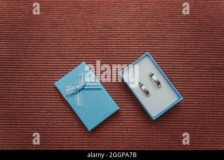 wedding rings in a blue box on red textured background top view Stock Photo