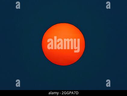 The Sun in bright red and orange color, with a dark background. Oregon, USA. Stock Photo