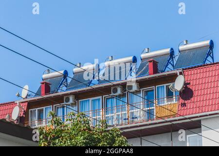 Thermal solar panels and water heater alternative technologies of water heating on the roof of the hotel against the blue sky outdoor. Stock Photo