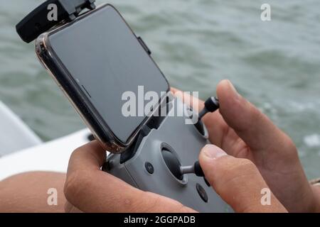Close-up, Young man operating aerial photography drone on a small boat Stock Photo