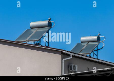 Thermal solar panels and water heaters alternative technology of water heating on the roof of the home against the blue sky. Stock Photo