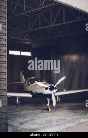 Small white private jet parked in the hangar Stock Photo