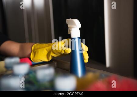cropped view of maid in rubber glove reaching spray bottle Stock Photo