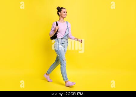 Full size profile photo of optimistic nice brunet lady go wear overall isolated on yellow background Stock Photo