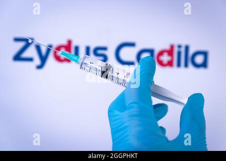In this photo illustration a hand in medical gloves hold a syringe in front of Zydus Cadila logo in Barcelona, Spain on September 2, 2021. Zydus Cadil Stock Photo