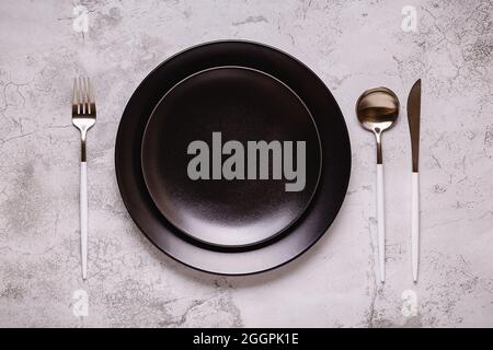Clean empty black plate with cutlery. Copy space, mock up, top view. Concept for menu with utensil. Stock Photo
