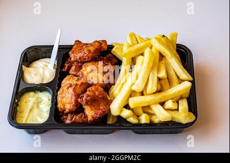 Dutch street food, portion of french fried potatoes, pieces of fried in oil cod fish fillet and two sauces close up Stock Photo