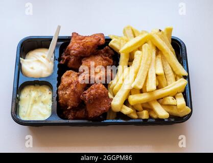 Dutch street food, portion of french fried potatoes, pieces of fried in oil cod fish fillet and two sauces close up Stock Photo