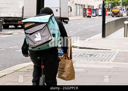 London, England - August 2021: Person working for Deliveroo riding a bicycle delivering an order Stock Photo