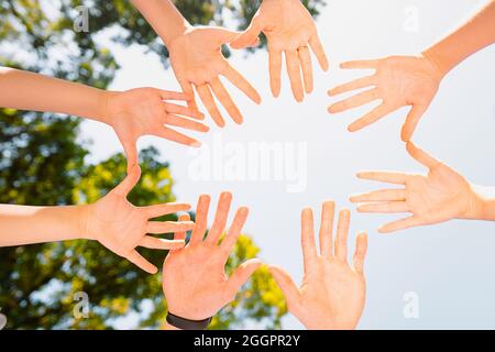 Close up bottom view photo of diverse people holding hands in circle showing unity and support and winning in teamwork. Stock Photo