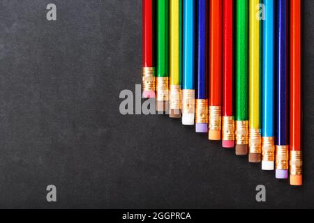 Colorful pencils with erasers in a row on a black background. Top view, free space Stock Photo