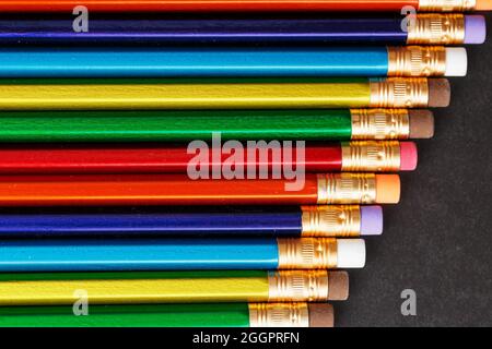 Colorful pencils with erasers in a row on a black background. Top view, free space Stock Photo