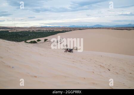Amazing view of parked motorbike on sandy dunes in desert. Sunny day during summer vacation. Sand dunes. Motorcycle in desert. Stock Photo