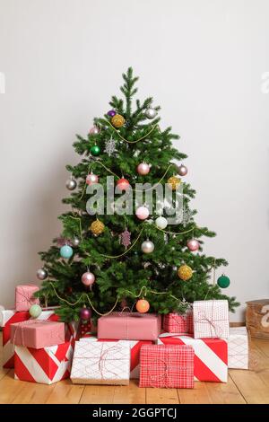 Wrapped boxes with gifts under a Christmas tree in a light room. Stock Photo