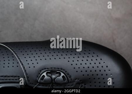 Sports shoes made of black perforated leather in a dark key. Close-up Stock Photo