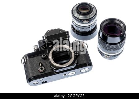 Horizontal shot looking down at a heavily used black professional camera body with a 35mm lens and a 105mm lens beside it isolated on white. Stock Photo
