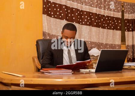 Smiling African businessman reading files by his desk Stock Photo