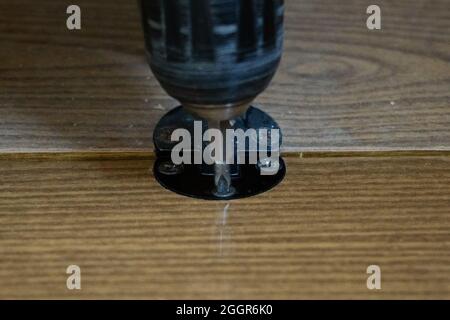 Screwdriver twists screw into antique furniture close-up Stock Photo
