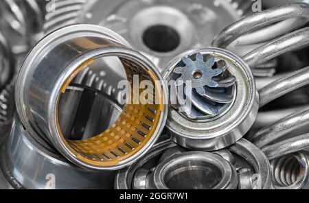 Detail a heap of hardware spare parts of a gear machine mechanism. Needle rolling bearing bushing with small steel rollers in cylindrical plastic cage. Stock Photo