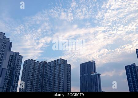 White Altocumulus Clouds Scattered on Light Blue Sky over the Group of Skyscrapers Stock Photo