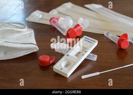 Covid-19 rapid antigen self test with negative result, nasal swabs, tubes and detecting device on a wooden table, used for mass diagnostic at home, at Stock Photo