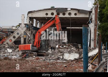 Orange excavator demolishes an old industrial building. Stock Photo