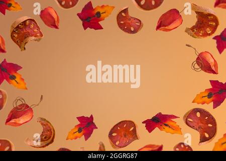 Creative autumn frame with colorful leaves and sliced dried pumpkin on a orange brown background. Minimal season concept. Copy paste. Stock Photo