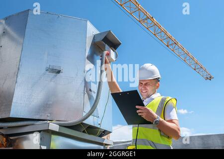 Engineer with clipboard checking the installation of the ventilation system Stock Photo