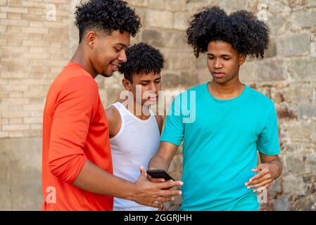 Multiethnic friends using mobile phone in the street Stock Photo
