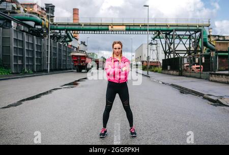Sporty woman looking camera posing in front of a factory Stock Photo