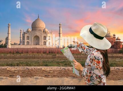 Female tourist hold a map and points at Taj Mahal from Mehtab Bagh at Agra India at sunset Stock Photo