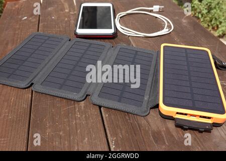 Portable solar panels with battery power bank storage charging a Iphone . Stock Photo