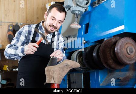 male worker fixing failed shoes in shoe repair workshop Stock Photo