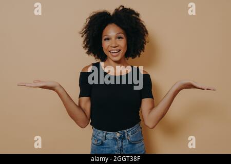 Unsure african female model shrugging shoulders with uncertainty with clueless and confused look Stock Photo