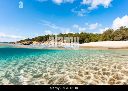 (Selective focus) Split-shot, over-under shot. Half underwater half sky with turquoise sea and a white sand beach with green vegetation. Stock Photo