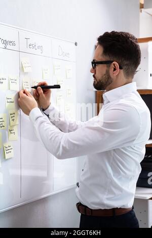 Man Writing Notes On Kanban Board In Office Stock Photo