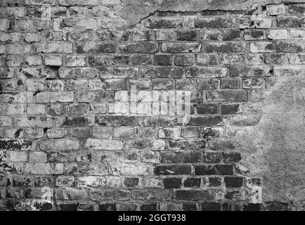 Front view of an old, dirty, damaged and plastered wall. Plaster is mostly peeled off revealing old bricks. High resolution full frame textured backgr Stock Photo