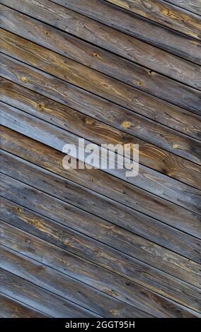 Weathered unpainted wooden wall or door with diagonal boards, front view. Abstract full frame textured background. Stock Photo