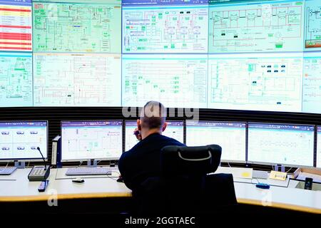 Karlsruhe, Germany. 18th Aug, 2021. An employee of the energy company EnBW sits in front of monitors in the control centre in unit 8 of the Rhine port steam power plant in Karlsruhe (RDK 8). Everyday life in a power plant is routine. The tension rises when fault messages are received. For power plant workers, there is an additional complication: constant shift changes including night work. (to dpa-KORR.: 'Shift work in the power plant: Sometimes only 20 seconds to react') Credit: Uwe Anspach/dpa/Alamy Live News Stock Photo