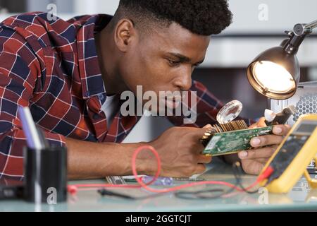 computer technician looking through magnifying glass Stock Photo