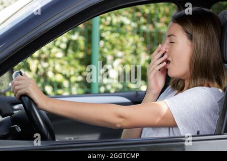 side view of a young woman yawning inside car Stock Photo