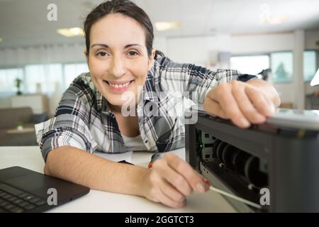 happy woman fixing a printer Stock Photo
