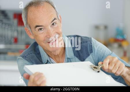 senior man looking in cupboard Stock Photo