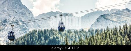 Two cabs of the cableway and skiers on the slope of the mountain Chopok south side on a sunny day in the ski Stock Photo