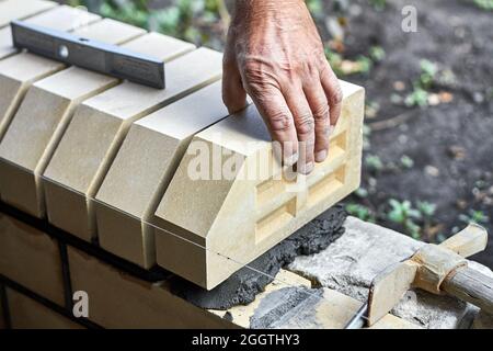 Bricklayer installing bricks on the new fence from facing bricks. Stock Photo