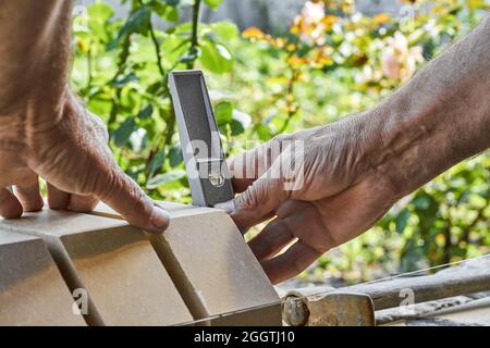 Bricklayer levelling bricks on the new fence from facing bricks using building level. Stock Photo