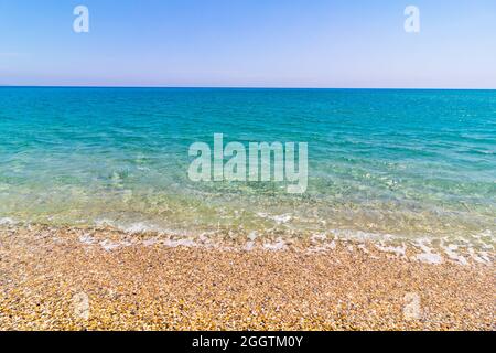 Pebbles on the seashore and turquoise sea with blue sky Stock Photo