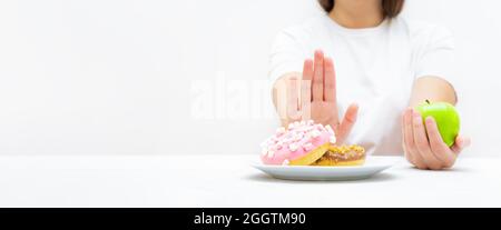 Woman on a diet making a choice between junk sweet food and fruits. Creative weight loss and healthy eating concept. Stock Photo