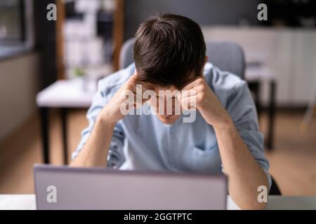 Unhappy Sad Man With Migraine Using Laptop Computer Stock Photo