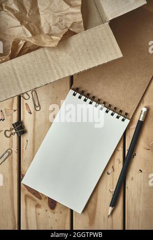Open Blank Spiral Notebook with Open Empty Cardboard Box and Black Pencil on Wood Table, Online Shopping Flat Lay Concept, Copy Space for Text. Stock Photo